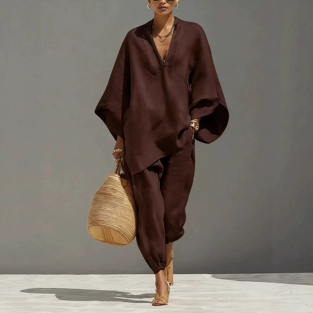 Model in dark brown batwing sleeve V-neck lounge set with woven bag, studio background.