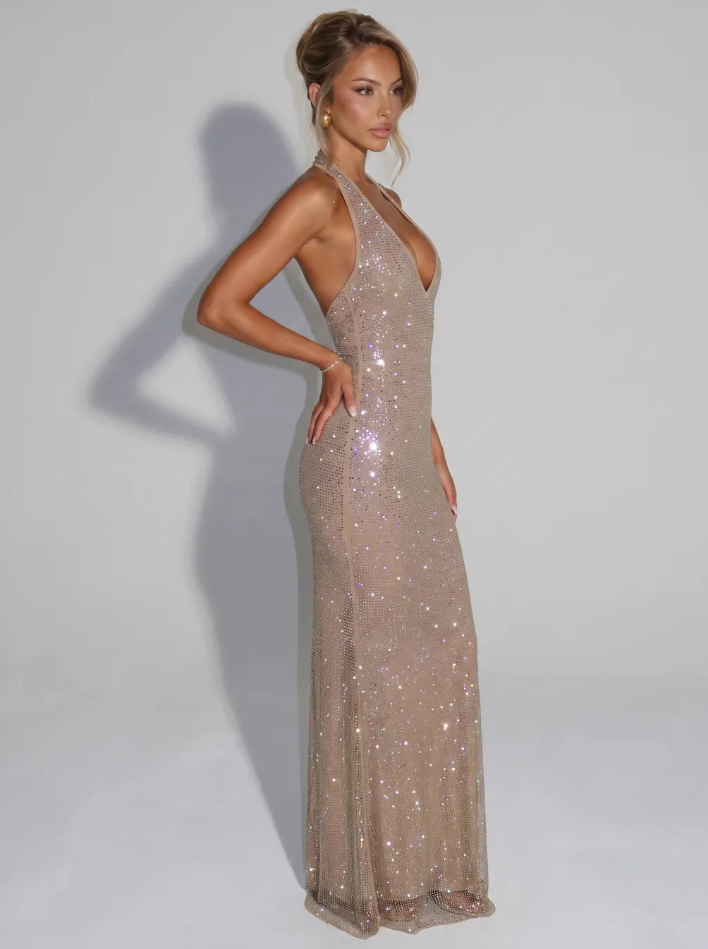 Side view of sleeveless, sequin midi dress with V-neck, worn by model in a studio setting.