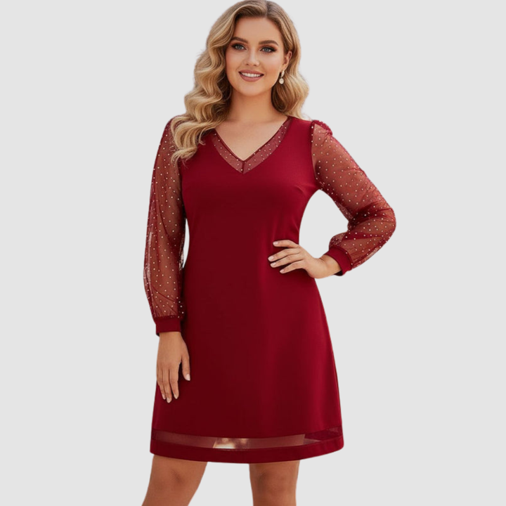 Elegant red dress with sheer polka dot sleeves, modeled in a studio setting.