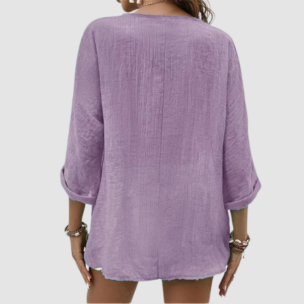 Back view of woman wearing a purple three-quarter sleeve blouse, accessorized with bracelets, against a plain background.