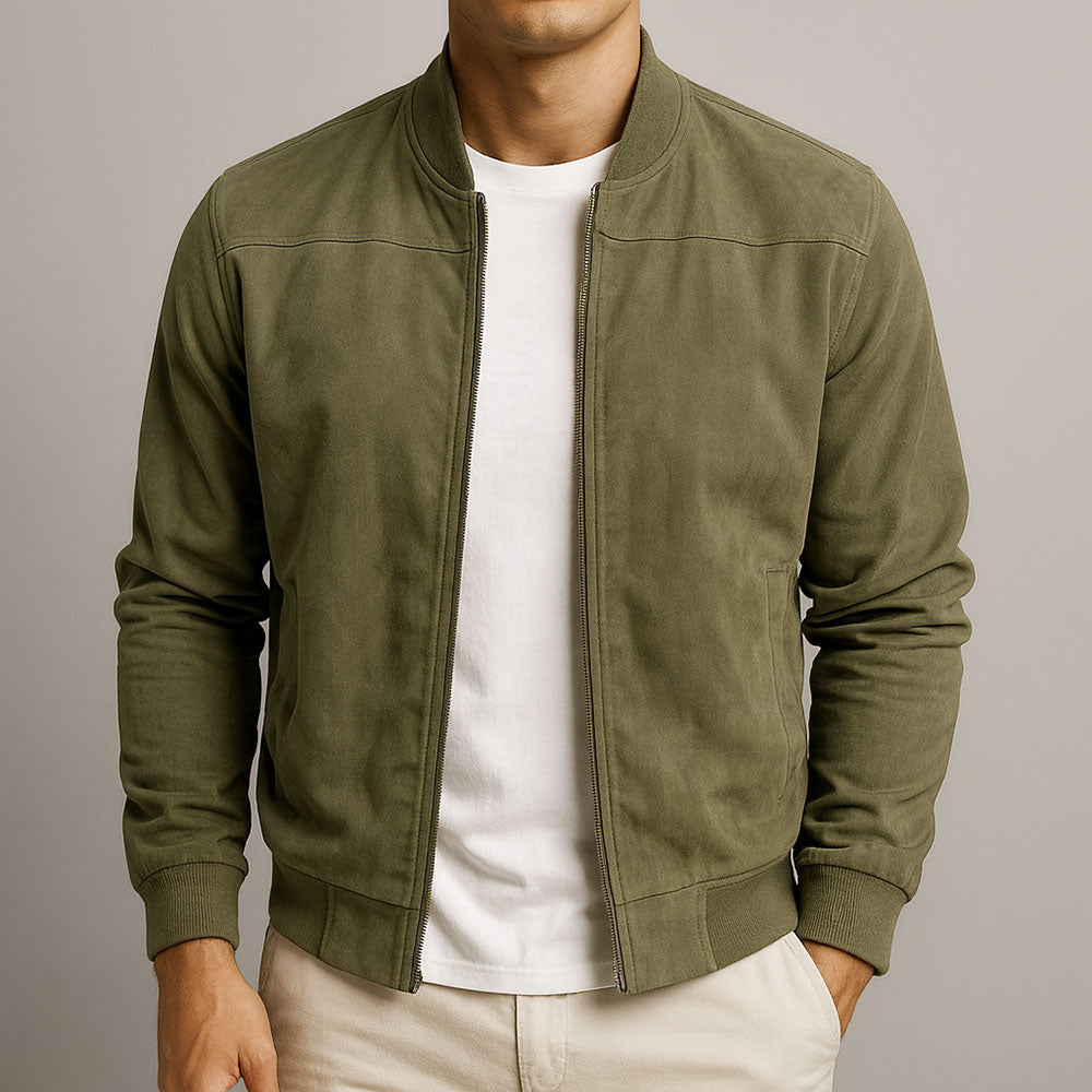 Man wearing an olive urban classic jacket, white shirt, and beige pants in a studio setting.