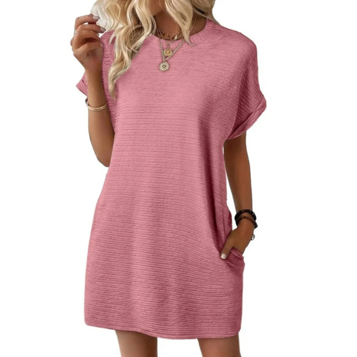 Soft blush pink casual dress with short sleeves and a loose fit, modeled with stylish jewelry in a studio setting.