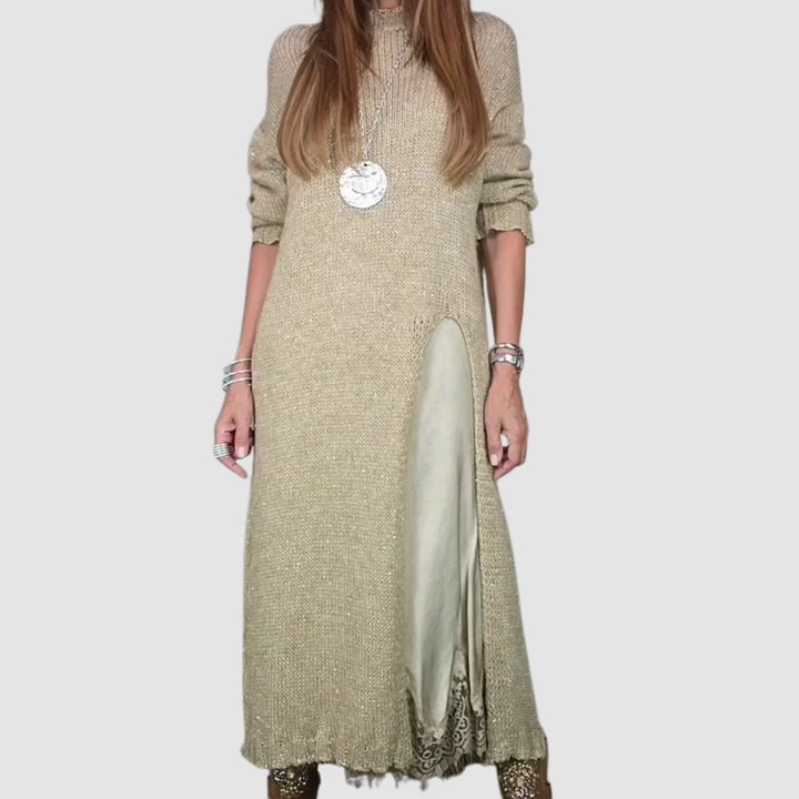 Woman in beige dress with layered skirt and pendant necklace, posing on a gray background.