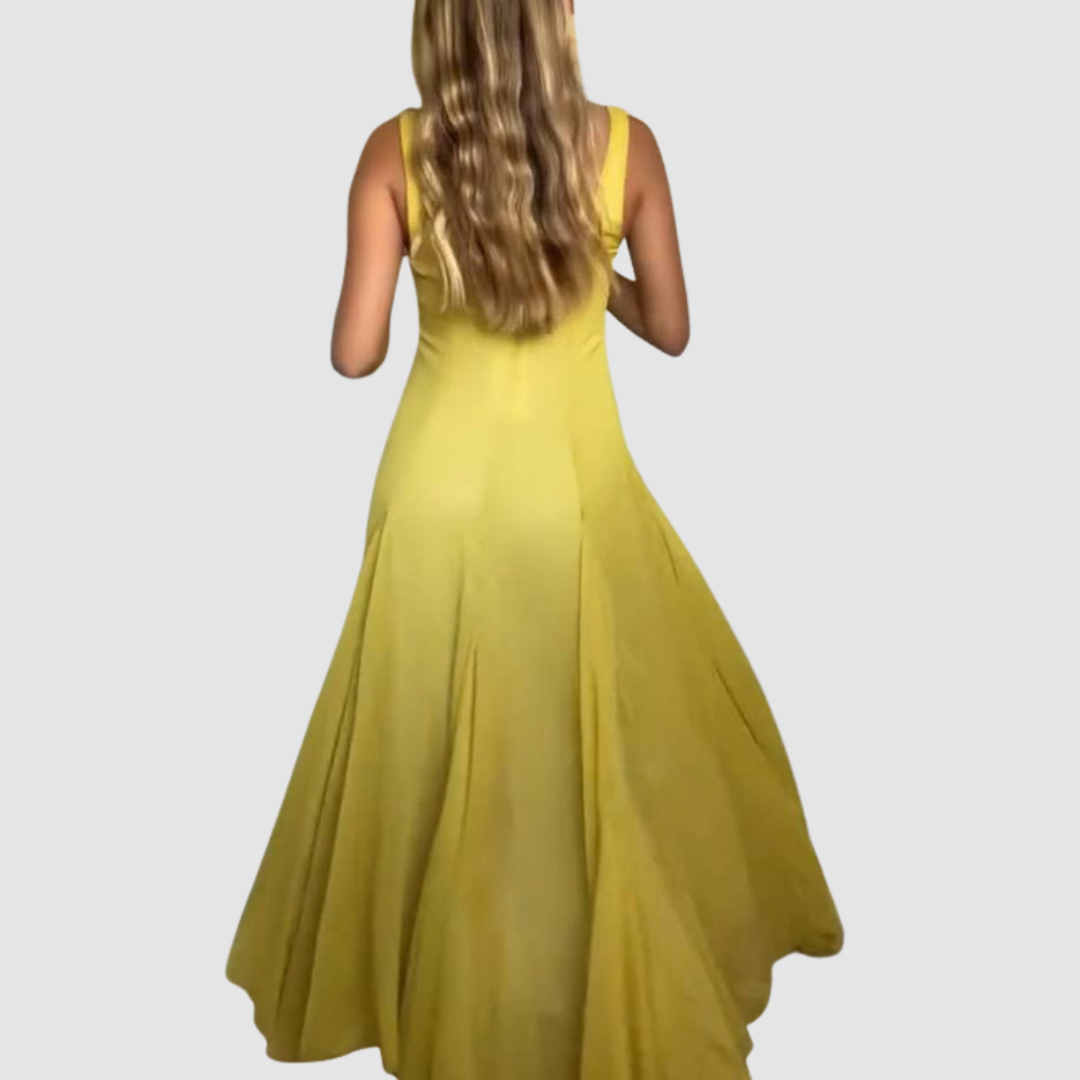 Back view of a yellow strappy maxi dress with flowing skirt, model posed in studio environment.