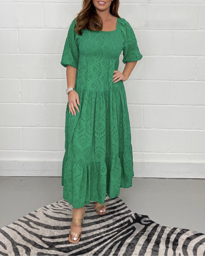 Green dress with eyelet accents, modeled indoors against a white brick wall with zebra-style rug.