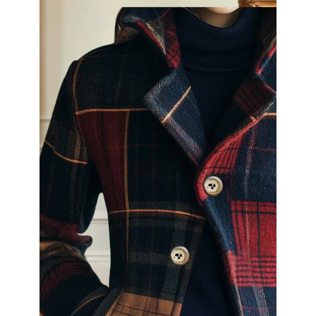 Close-up of a classic red and blue plaid jacket with visible buttons, over a navy turtleneck. White indoor background.