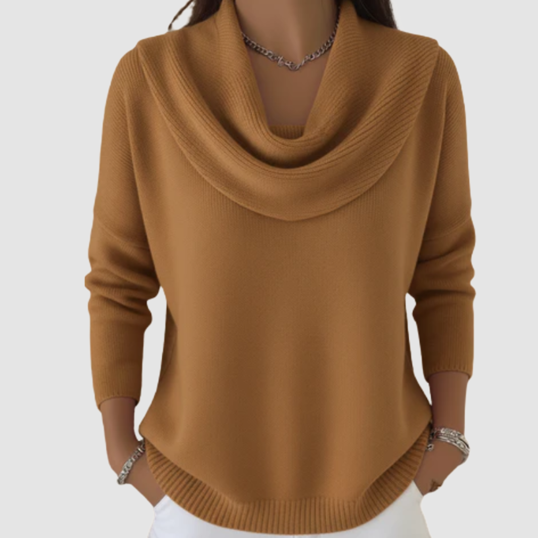 Camel cowl neck sweater with long sleeves worn over white pants, displayed in a studio setting.