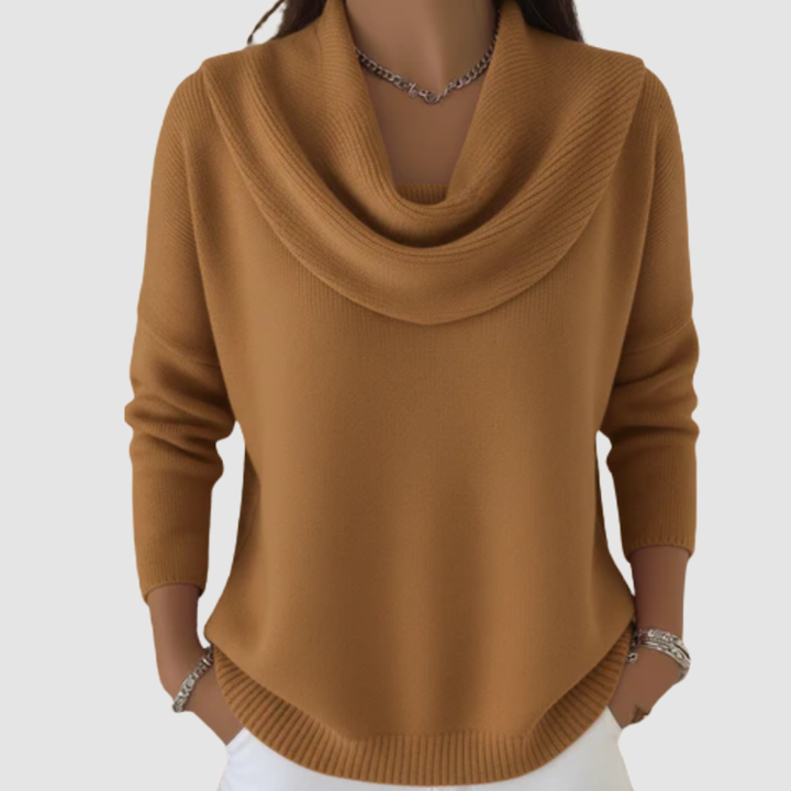 Camel cowl neck sweater with long sleeves worn over white pants, displayed in a studio setting.