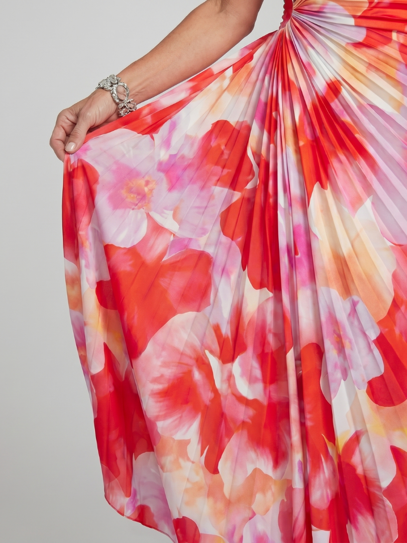 Close-up of red floral pleated fabric from one-shoulder dress in studio lighting.