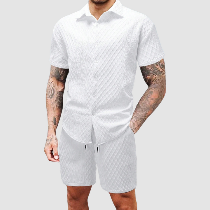 White short-sleeve shirt and shorts with textured pattern on a man against a light gray background.