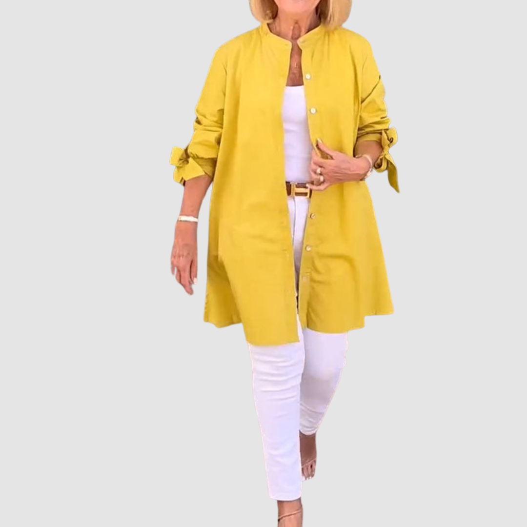 Person wearing a yellow long-sleeve shirt over a white top and pants, standing on a light gray background.
