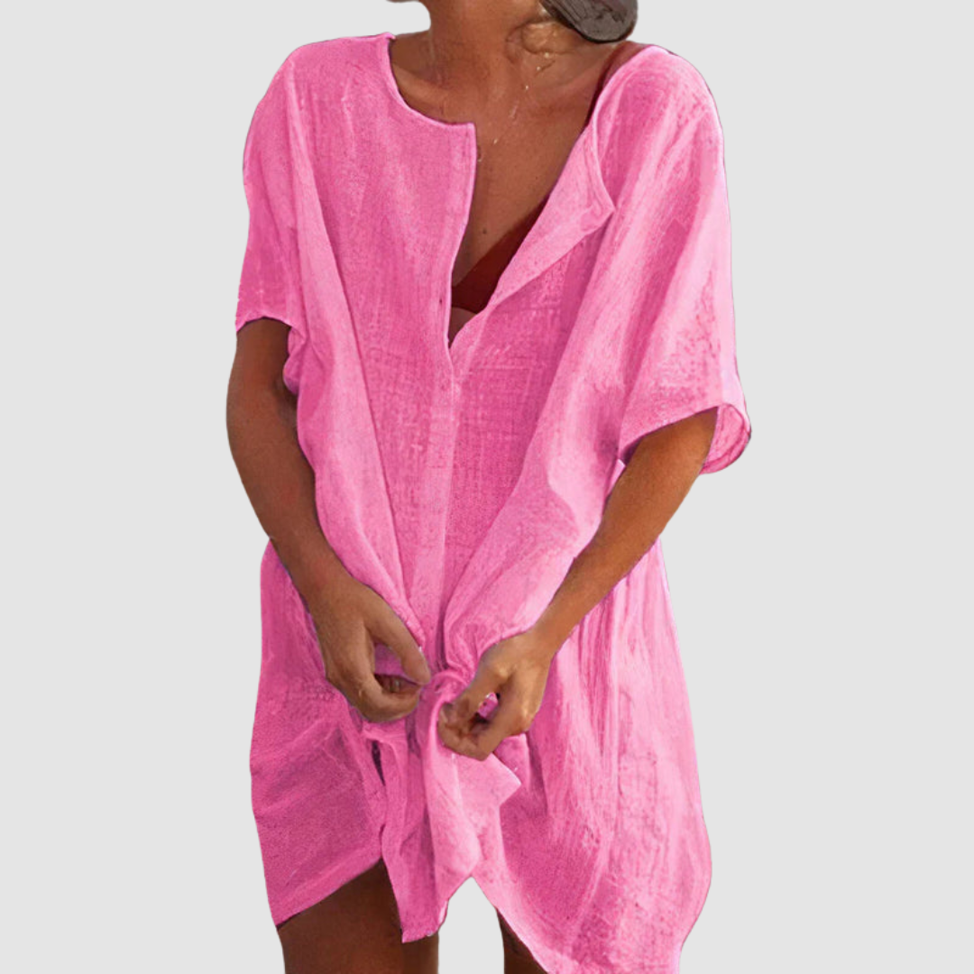 Pink loose fit dress with short sleeves and textured fabric, worn by person with untied front, studio background.