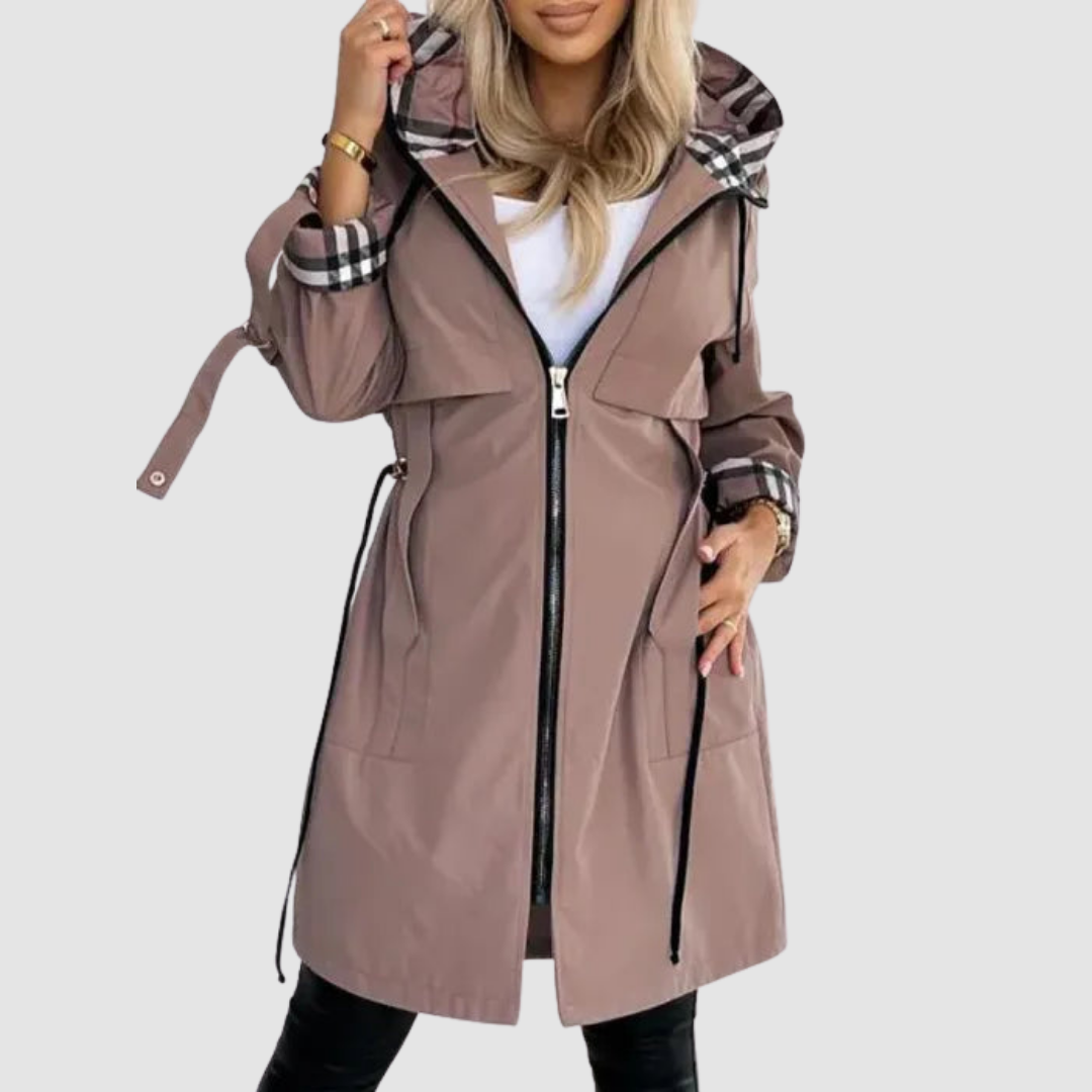 Light brown waterproof zip coat with plaid-lined hood and cuffs, worn over a white top and leggings, against a white background.