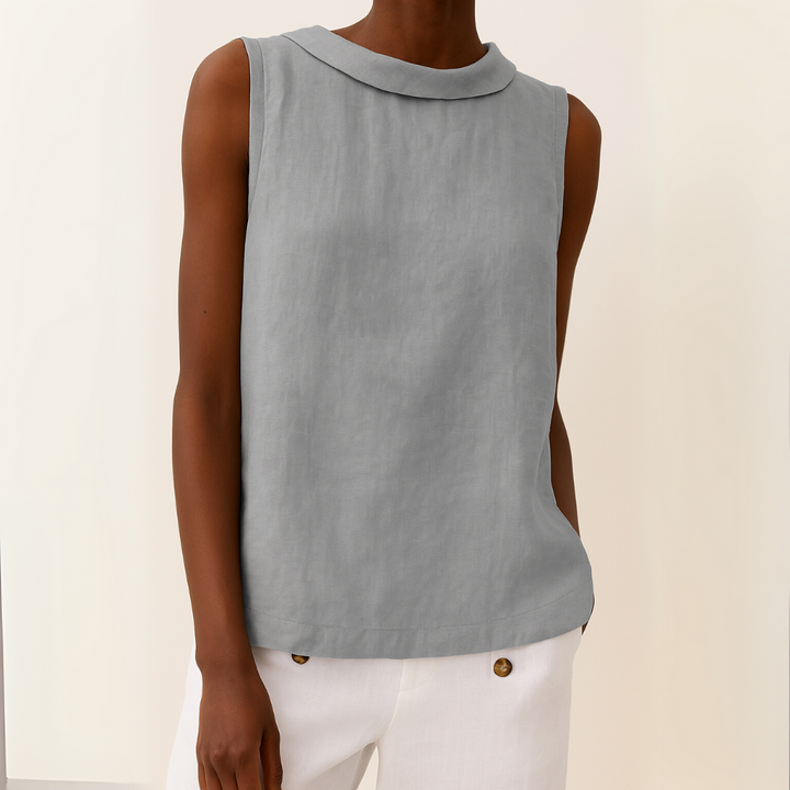 Grey sleeveless top with roll collar on model, paired with white pants against a light background.