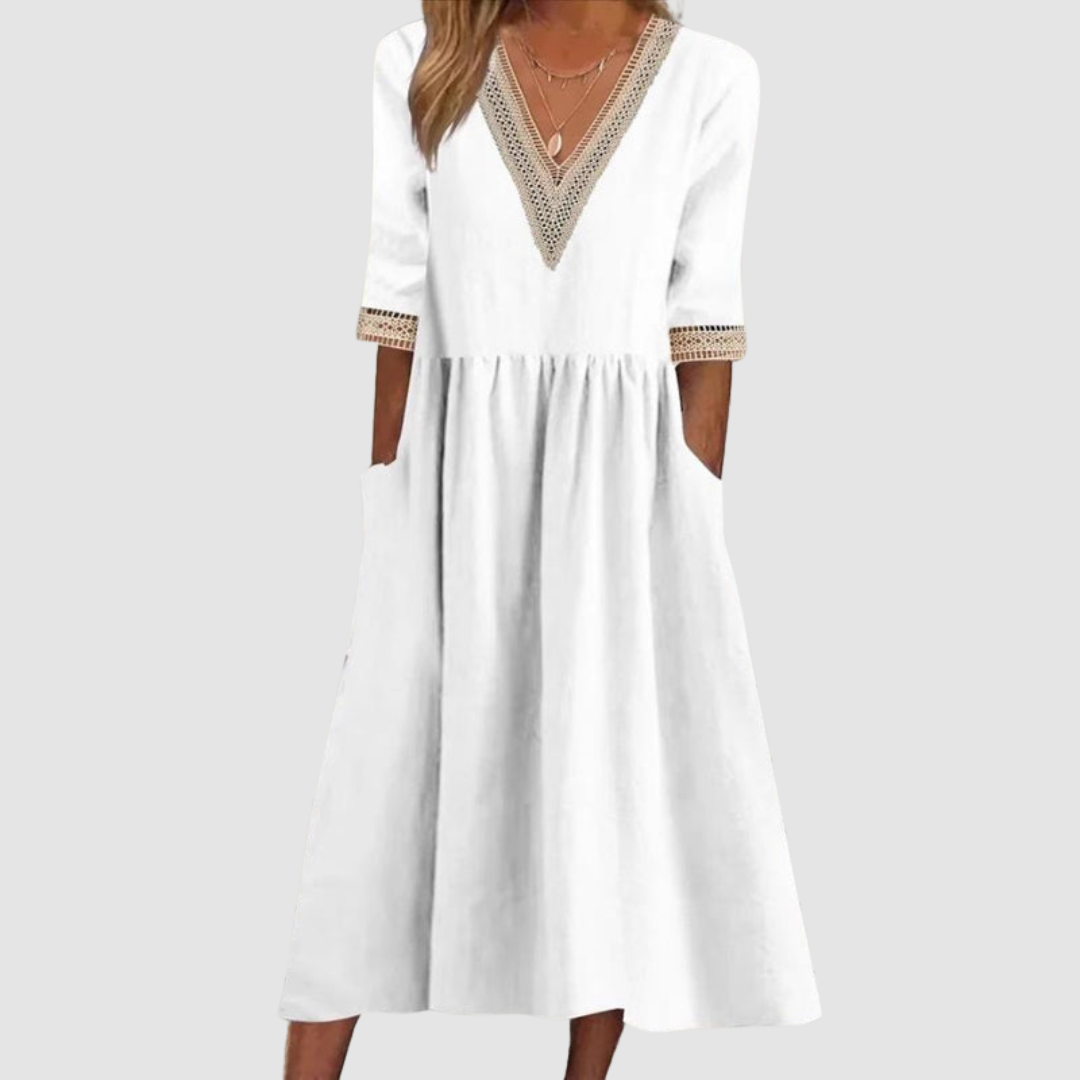 White mid-length dress with crochet trim neckline and sleeves, styled in a studio on a light gray background.