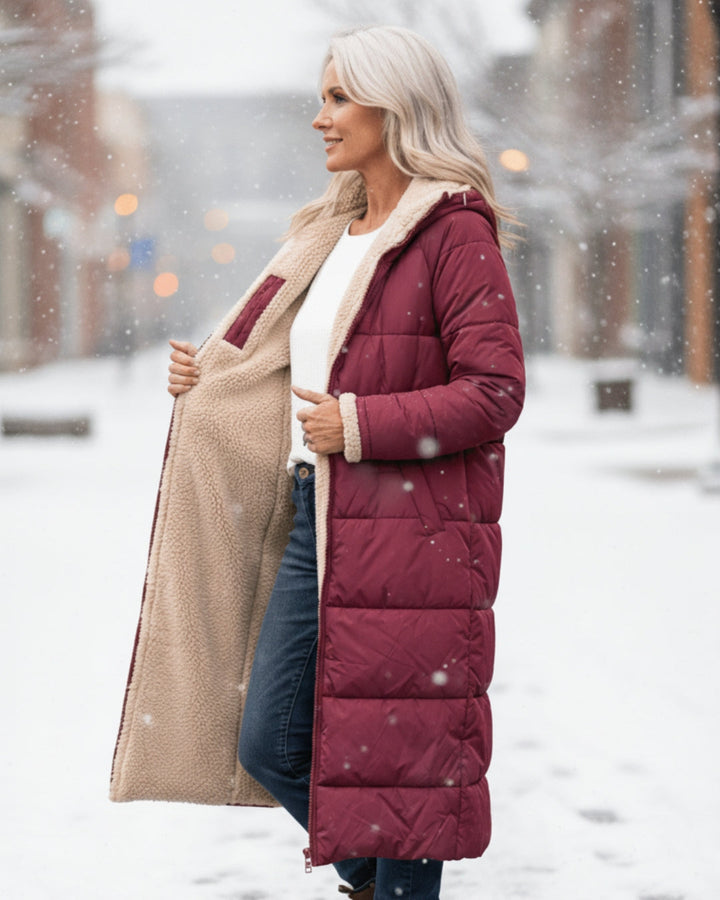 Woman displays fleece lining of red coat, standing in a snowy city street.
