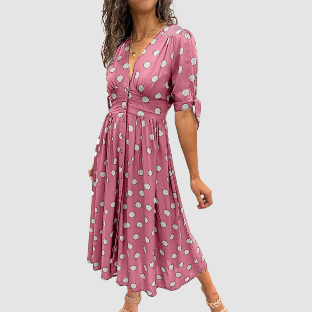 Pink dress with white polka dots, V-neck, tied sleeves, knee-length, studio setting.
