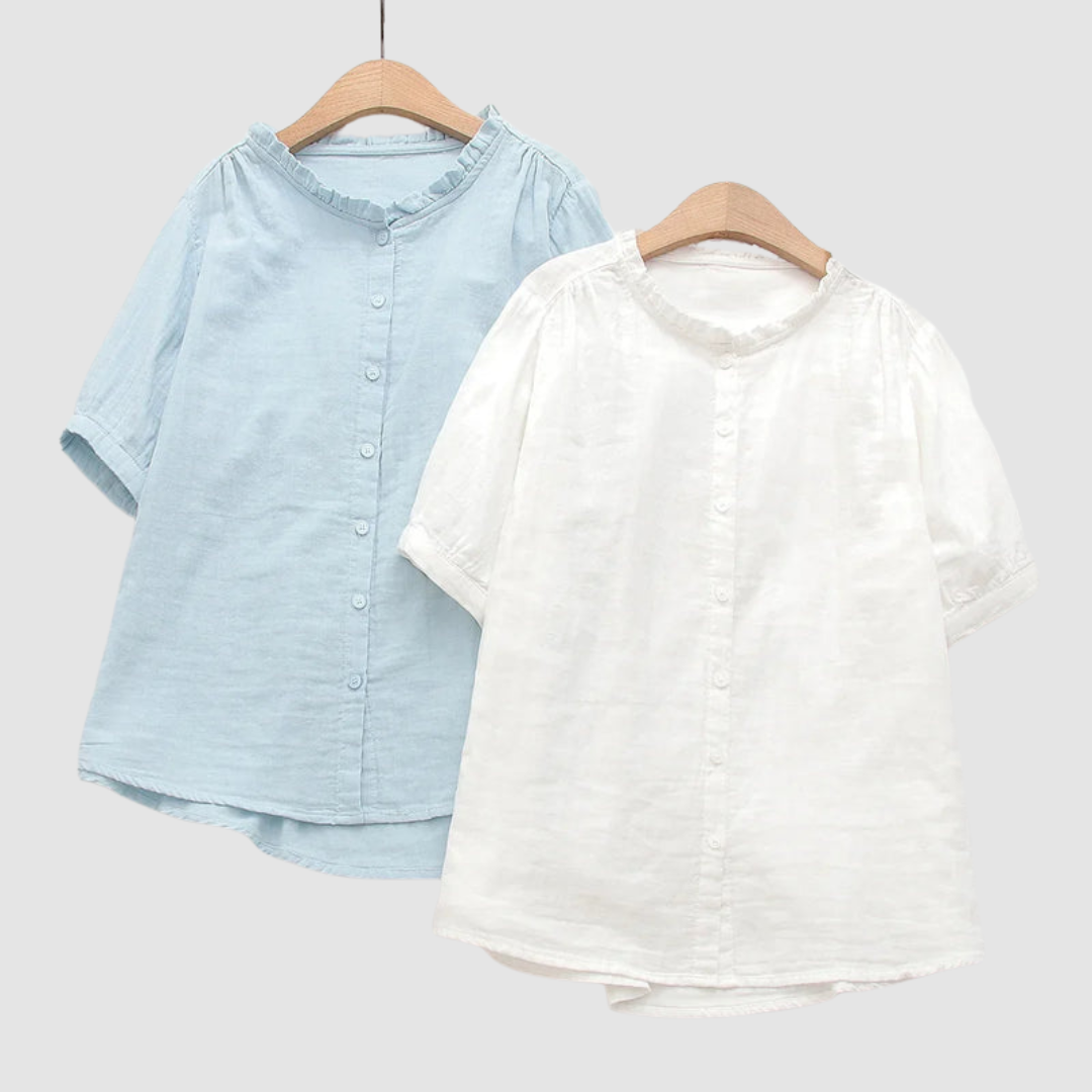 Two shirts on hangers, one light blue and one white, with ruffled collars, studio background.