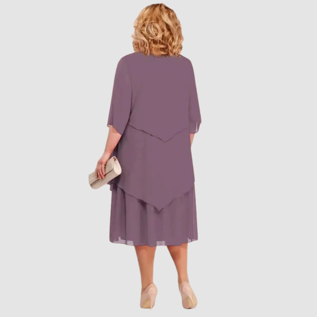 Back view of purple chiffon midi dress with layered design, shown with beige clutch on white background.