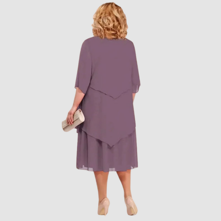 Back view of purple chiffon midi dress with layered design, shown with beige clutch on white background.