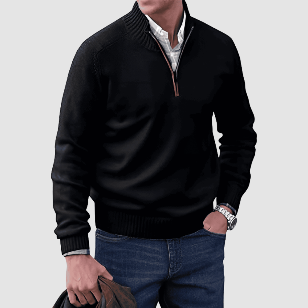 Model in black zip pullover with ribbed collar and cuffs, holding a jacket. Paired with jeans, set against a plain background.