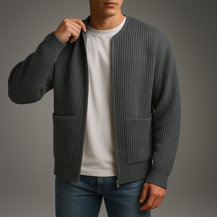 Model in a dark gray knit zip cardigan over a white shirt and jeans in a studio.