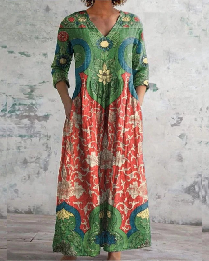 Colorful vintage floral dress with intricate patterns against a textured, rustic indoor backdrop.