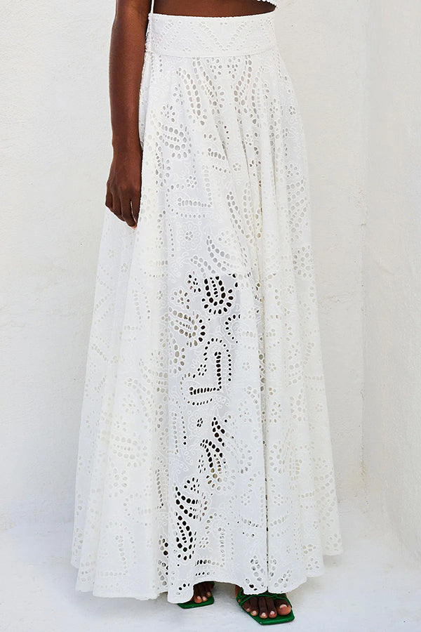 Model in a white embroidered high-waist maxi skirt with partial view against a plain white wall.