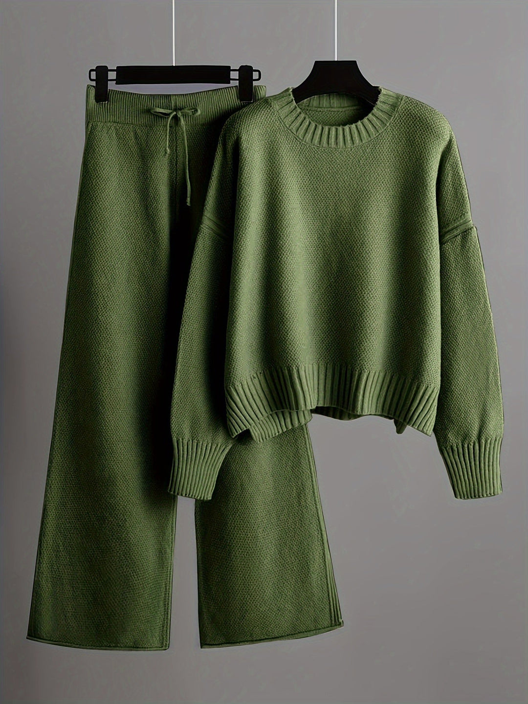 Olive green knit loungewear set featuring a cozy sweater and soft pants on hangers, gray background.