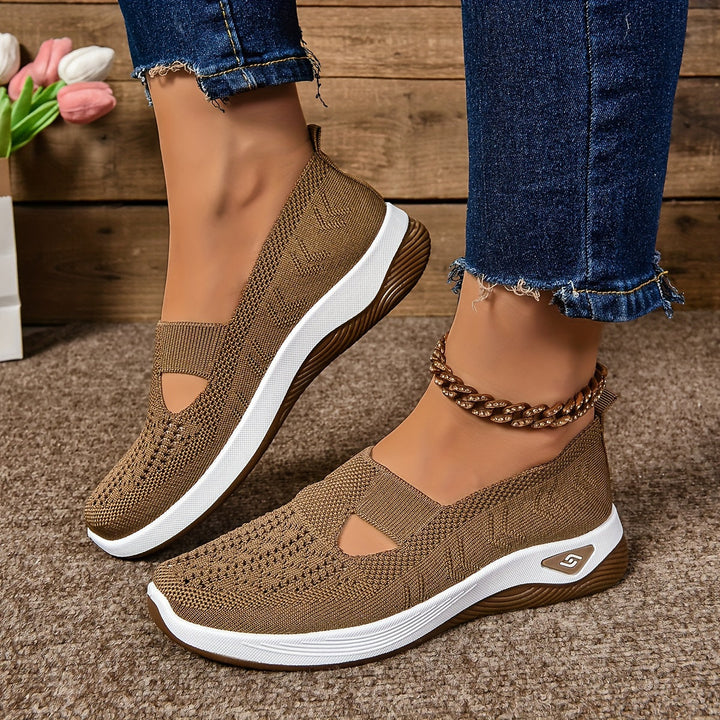 Brown non-slip orthopedic shoes worn with anklet, denim jeans on carpeted floor.