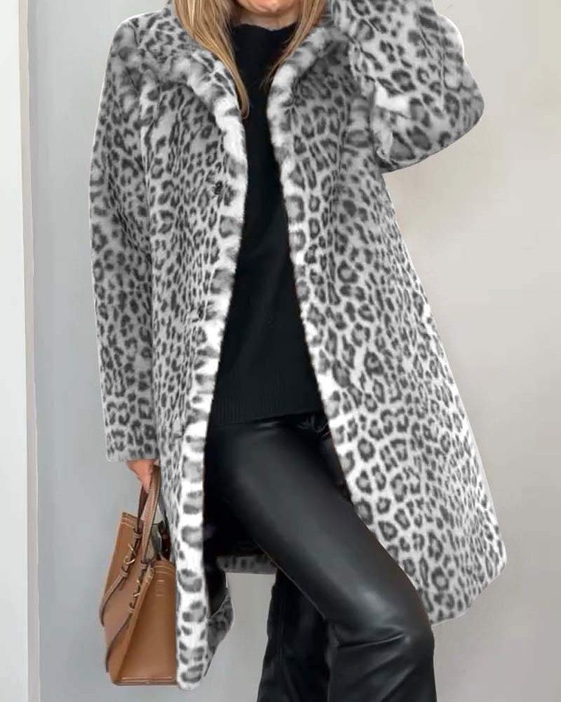Woman in a grey leopard print coat, styled with a black outfit and brown handbag against a plain indoor background.