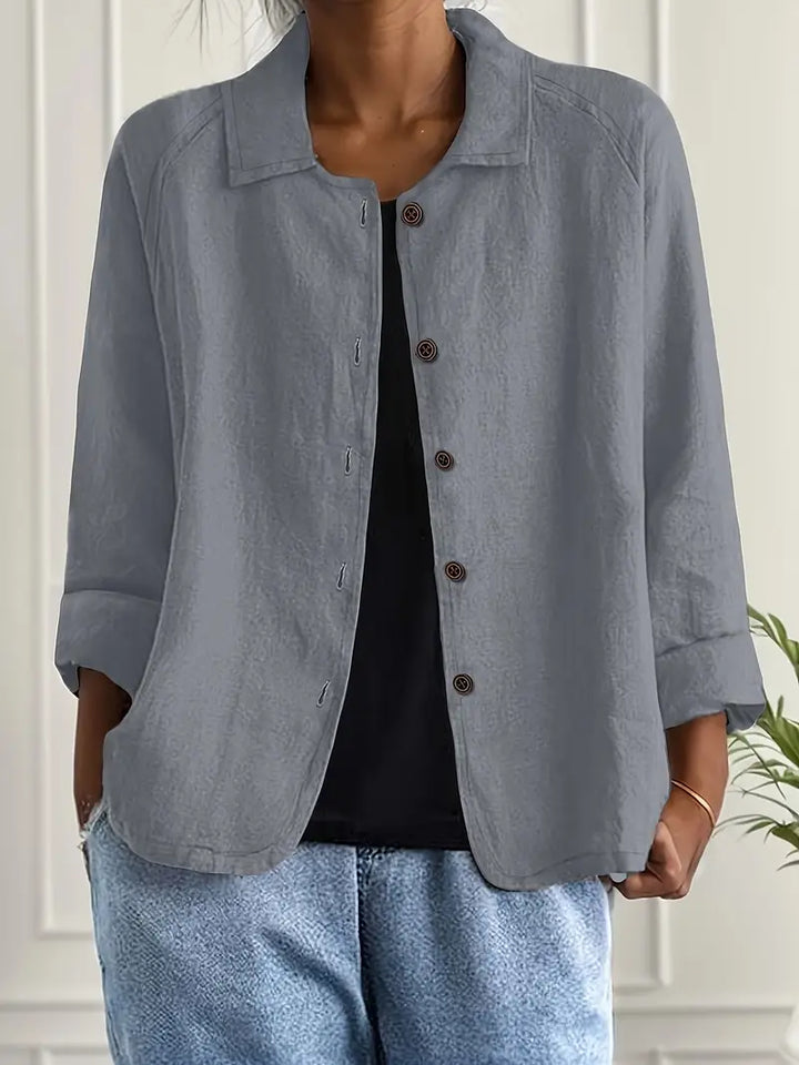 Gray button-up top with rolled sleeves, worn over black shirt in an indoor setting.