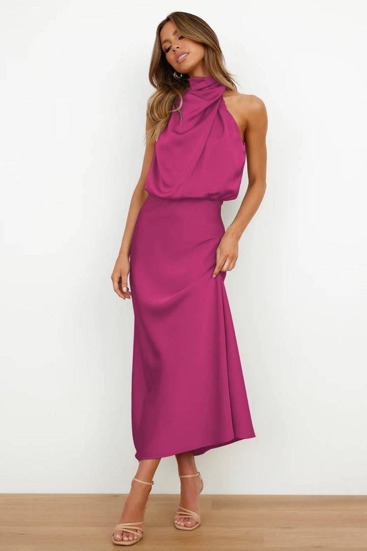 Magenta sleeveless halter dress with flowing design in a minimal indoor setting.