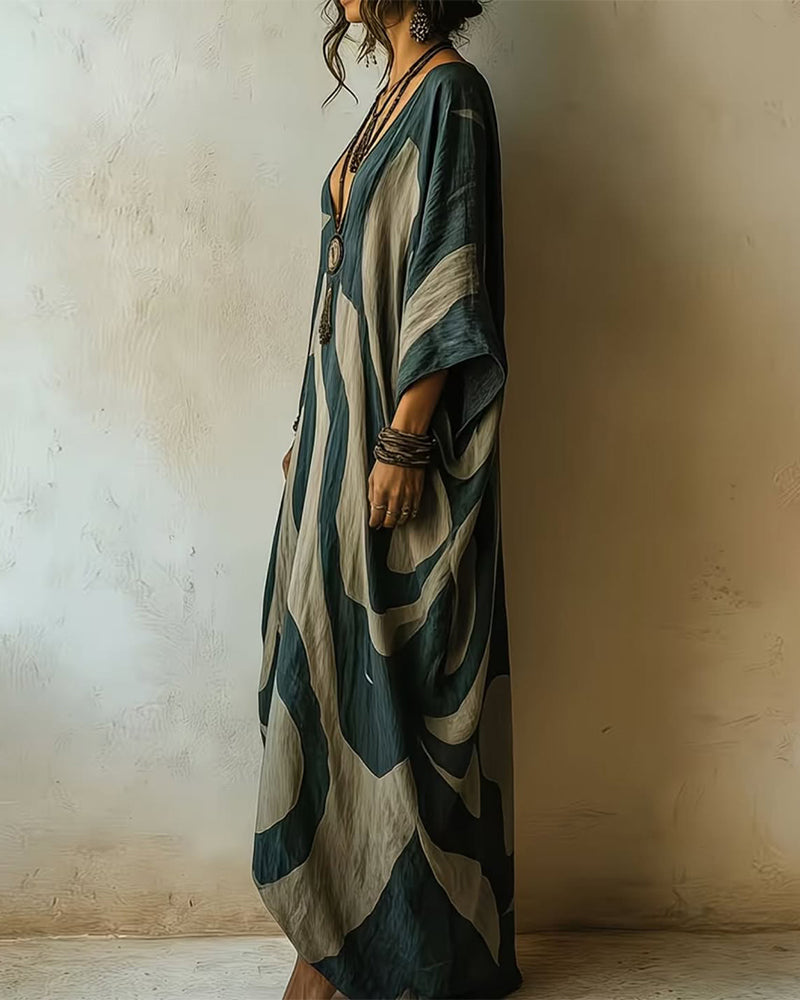 Side view of maxi dress featuring bold patterns, accessorized with layered necklaces, in a textured indoor setting.