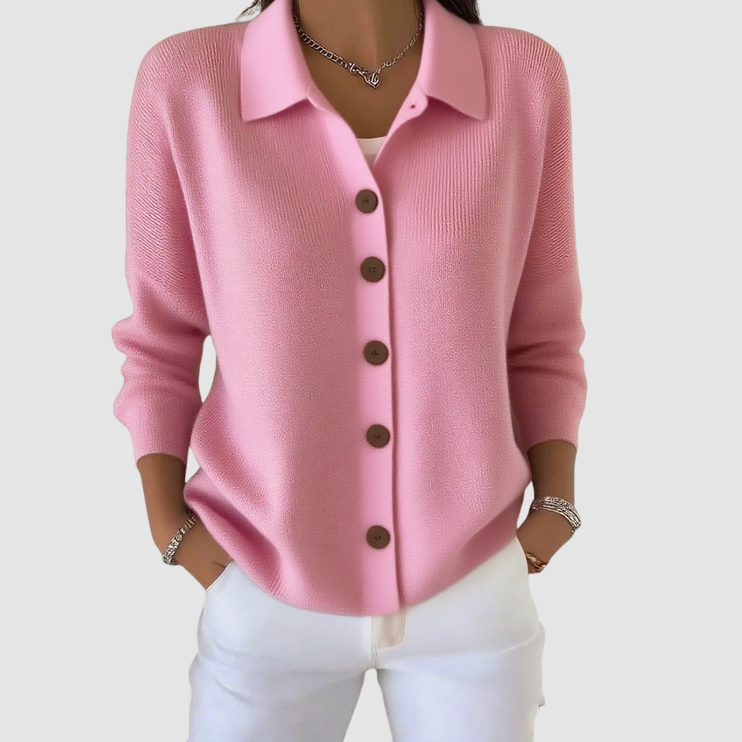 Pink button-up knit cardigan with brown buttons, worn with white pants in a studio setting.
