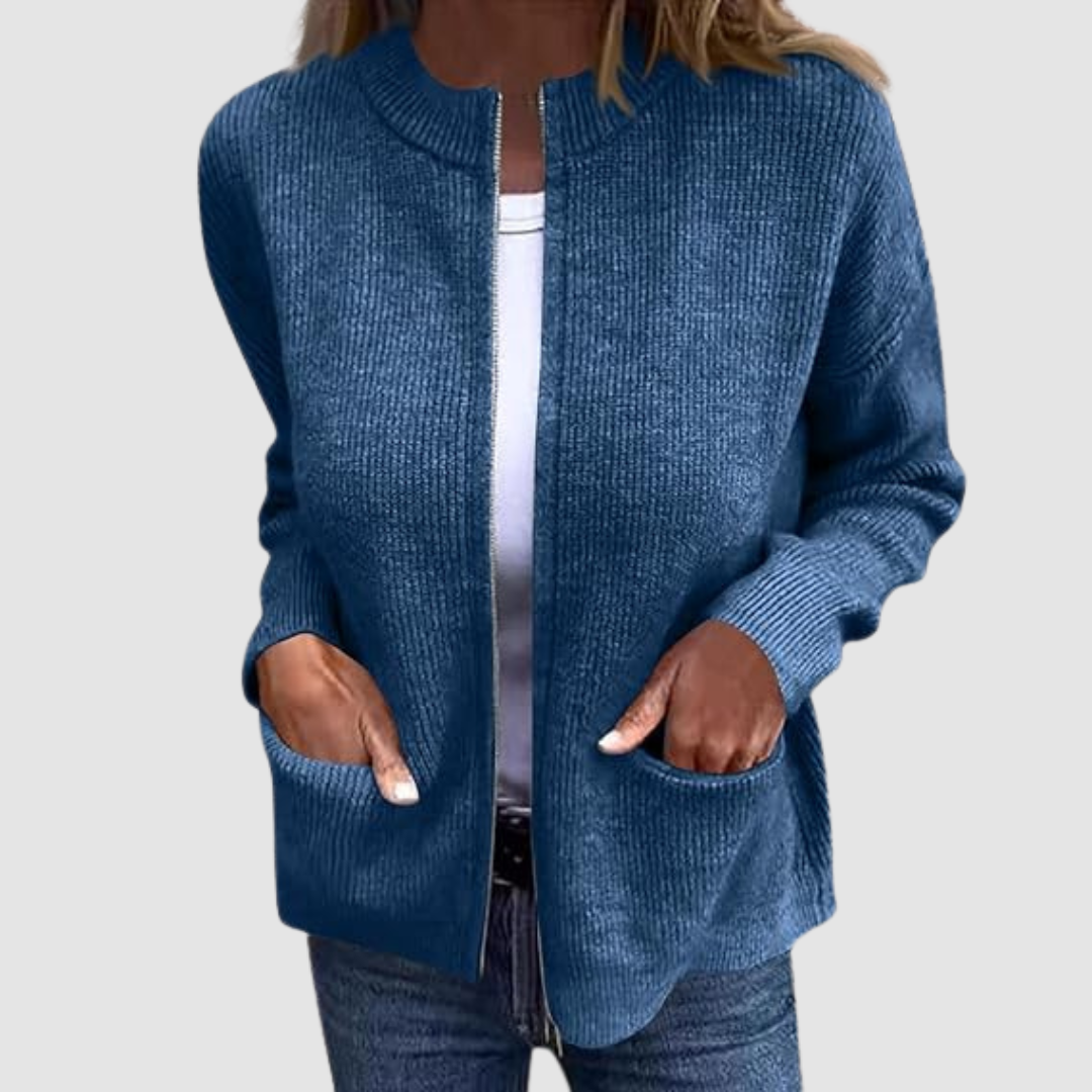 Blue cozy cardigan worn over a white t-shirt with hands in pockets. Neutral background.