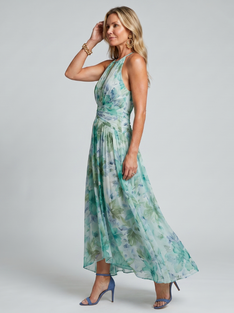 Side view of woman wearing green floral maxi dress and blue heels in studio setting.