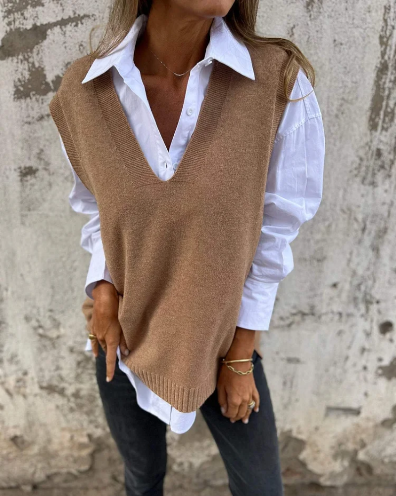 Beige knit vest over white shirt, worn by a person in front of a textured wall.