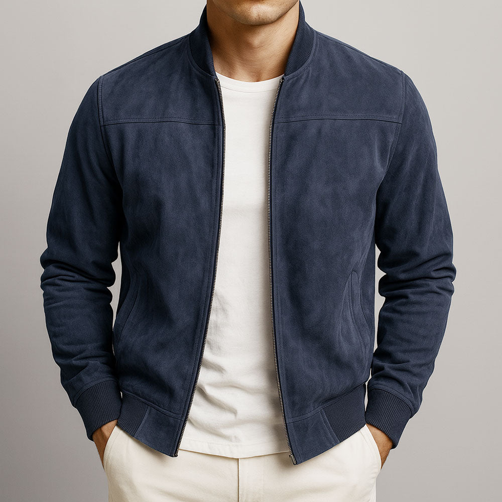 Man wearing a navy urban classic jacket, white shirt, and beige pants against a neutral backdrop.