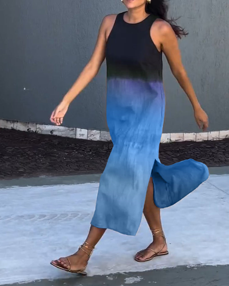 Woman in a sleeveless, ombre black to blue dress walking along an outdoor stone path.