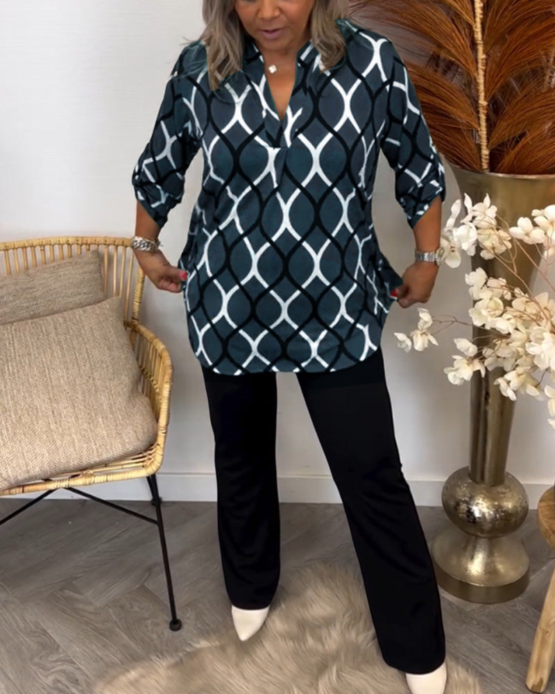 Person smoothing a blue and white blouse paired with black pants, surrounded by a chic room setting with wicker chair and florals.