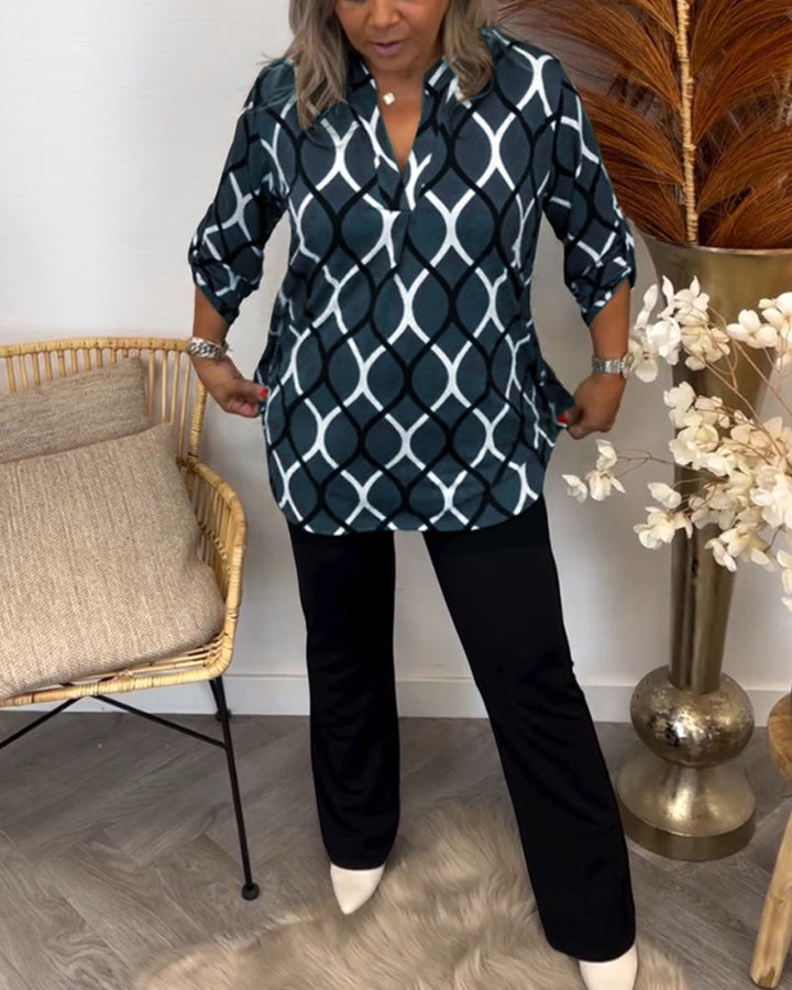 Person smoothing a blue and white blouse paired with black pants, surrounded by a chic room setting with wicker chair and florals.