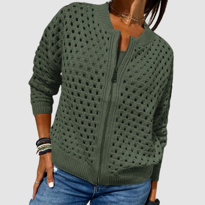 Dark green knitted cardigan featuring a zipper and perforated pattern, styled with blue jeans in a studio setting.