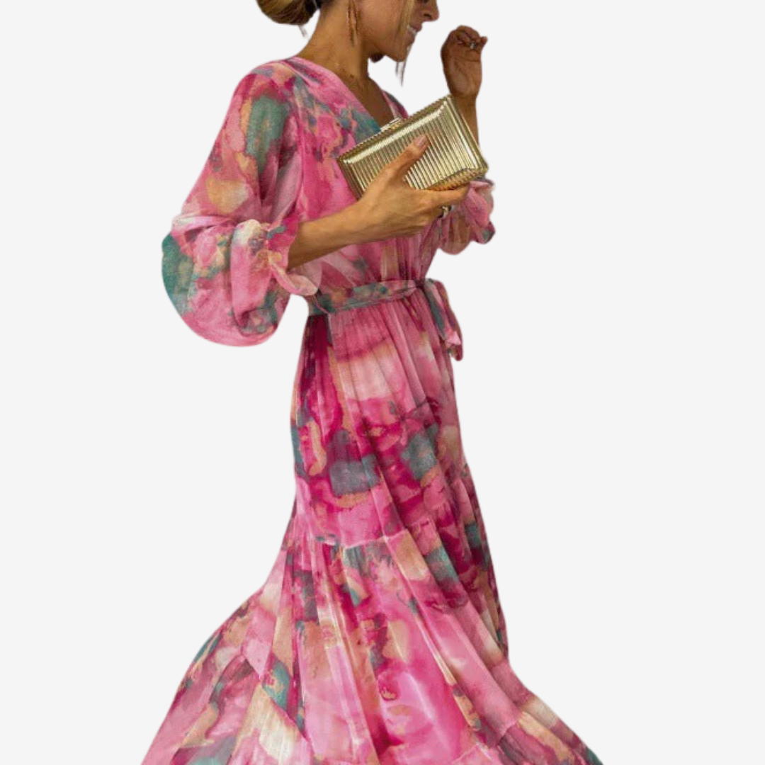Side view of a pink dress with vibrant patterns, puffy sleeves, and a belted waist. Model carrying gold clutch in studio setting.
