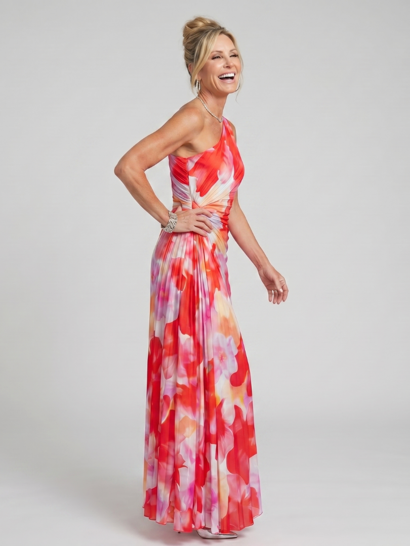 Model laughing in red floral one-shoulder pleated midi dress in studio setting.