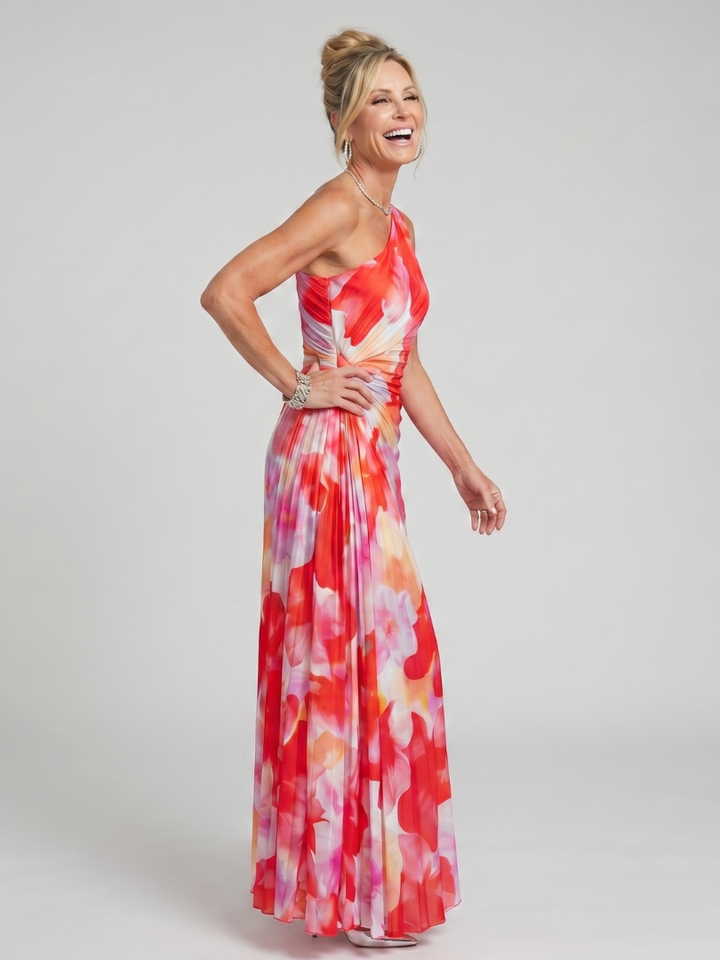 Model laughing in red floral one-shoulder pleated midi dress in studio setting.