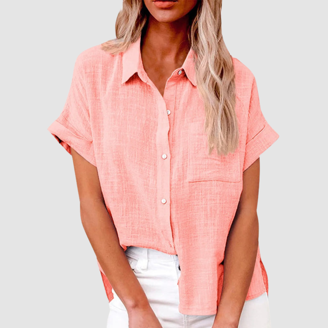 Peach pink casual blouse with short sleeves and front buttons, worn in white jeans. Studio background.