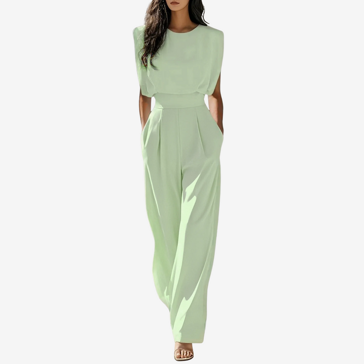 Light green sleeveless jumpsuit with wide legs, worn by model in studio setting, hands in pockets.