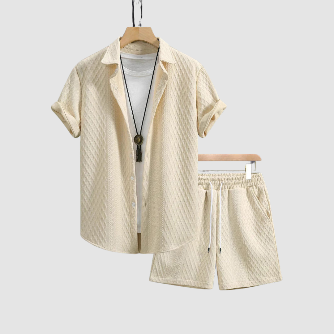 Beige short-sleeve shirt and shorts on hangers, with a white T-shirt underneath, against a light gray background.