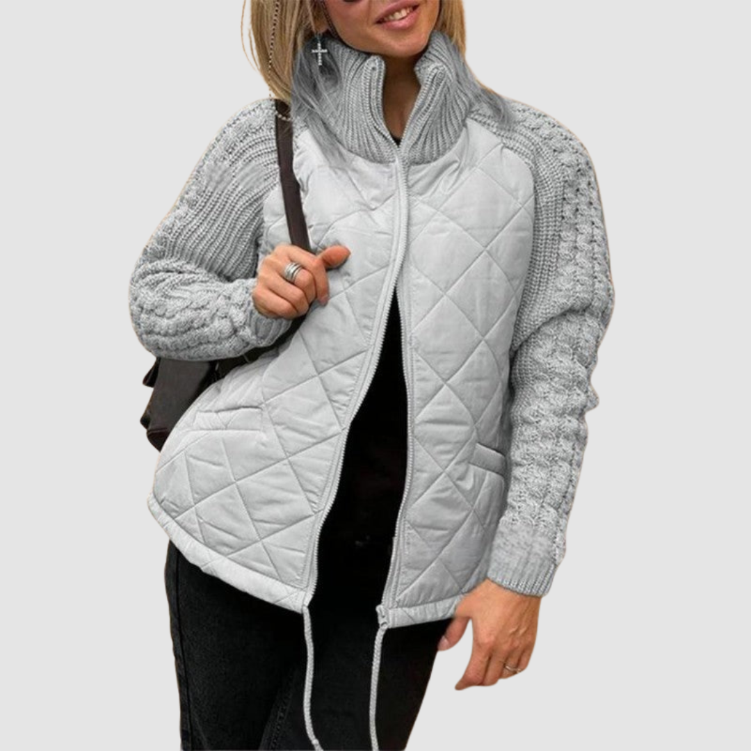 Light grey quilted jacket with knit sleeves, worn by a person in casual setting.